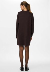 Vestido suéter marrón de gran tamaño con mangas largas, puños acanalados y cuello redondo. Textura suave y diseño a la altura de la rodilla.