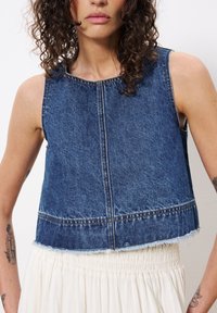 Blaue Jeans-Weste ohne Ärmel mit ausgefranstem Saum und tonalen Nähdetails. Verfügt über einen runden Ausschnitt und einen lockeren Schnitt, der eine glatte Textur zeigt.