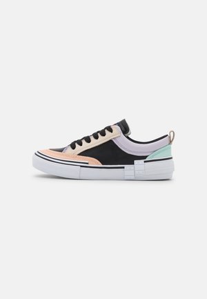 Niskie sneakersy łączące różne materiały w pastelowych i czarnych odcieniach, z teksturowaną cholewką, białą podeszwą i kontrastowymi akcentami na pięcie.