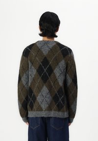 Il maglione lavorato a maglia presenta un motivo argyle grigio, nero e verde oliva con una texture pelosa. Vestibilità ampia e orlo a coste.