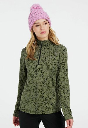Maglia verde a manica lunga con motivo a macchie nere, colletto alto e chiusura a mezza zip. Abbinata a un berretto lavorato a maglia rosa con pompon.