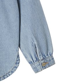 Light blue denim long sleeve shirt cuff with button closure and visible seams on plain white background.