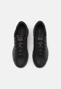 Sneakers neri con lacci realizzati in materiale sintetico liscio, con punta arrotondata, caratterizzati da un logo discreto sulla linguetta e un interno imbottito per il comfort.