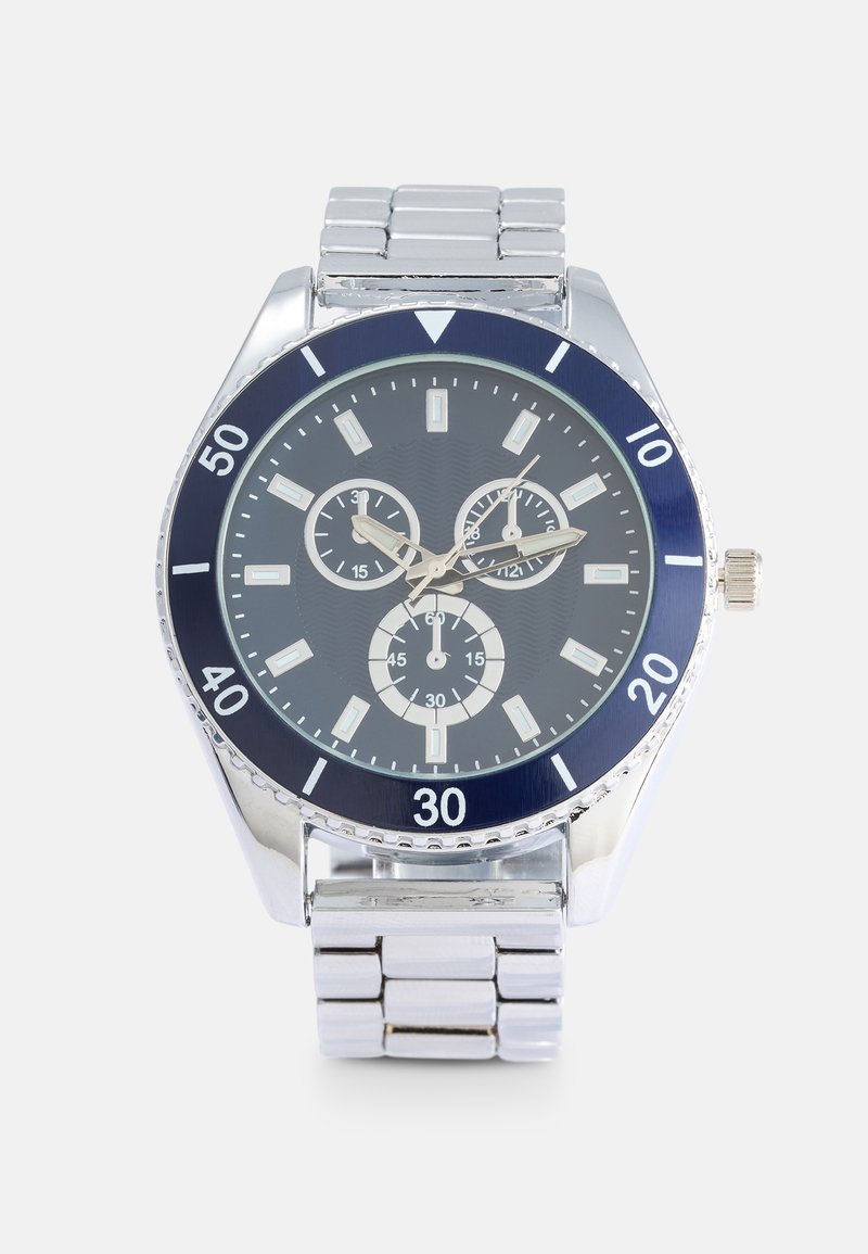 Orologio da polso in acciaio inossidabile argentato con un bezel blu navy, tre sottodial e indicatori delle ore argentati su uno sfondo testurizzato blu scuro.