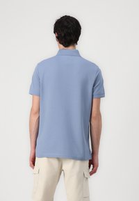 Polo shirt azzurro chiaro con maniche corte e colletto classico. Realizzato in un tessuto morbido, presenta un design pulito e un orlo dritto.