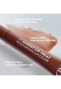 Leppestift i brun tube med hvit tekst. Glatt, glossy formelprøve i lysebeige på hvit bakgrunn. Inneholder peptider og sheasmør.