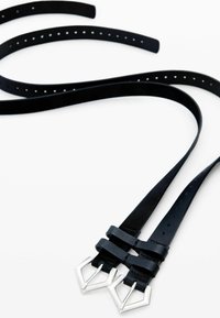 Cinturones de cuero negro con doble hebilla geométrica plateada y múltiples agujeros de perforación, dispuestos planos con los extremos superpuestos.