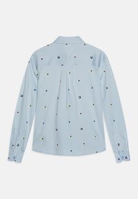 Camicia a maniche lunghe azzurro chiaro con colletto, decorata con un motivo a piccoli quadrati di vari colori disposti in modo sparso.