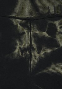 Černé žebrované legíny s jemným olivově zeleným vzorem, s hladkým povrchem a elastickým pasem.