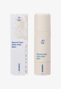 Baume multi-stick couleur naturelle de Korres dans un conteneur cylindrique beige et une boîte rectangulaire assortie, étiquetée 45+ / 100 et 4,5g de poids net.