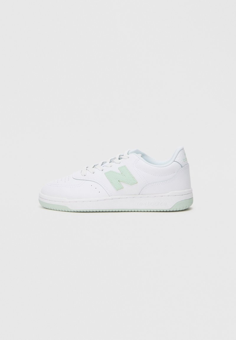 Zapatilla blanca con acentos verde claro. Hecha de cuero suave, presenta perforaciones, cordones y una suela de goma texturizada.