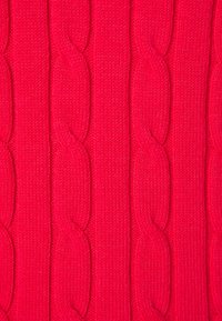 Tissu en tricot rouge présentant un motif de câbles avec des sections surélevées et torsadées. Texture lisse avec un tissage uniforme.