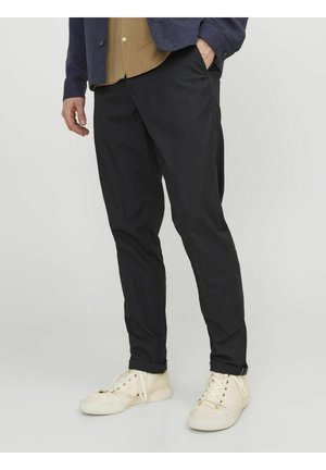 Pantaloni neri realizzati in tessuto leggero, caratterizzati da una vestibilità slim e tasche laterali. Indossati con sneakers color crema e una camicia con colletto.