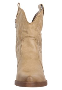 Botas de vaquero de cuero color marrón claro con punta afilada, costuras decorativas y una tira para facilitar el calzado; tienen una textura suave y un tacón bajo apilado.