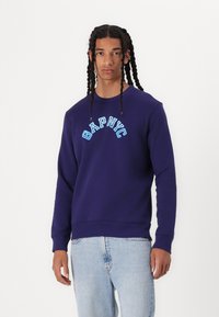 Navy blue sweatshirt featuring "GAP NYC" in light blue text across the chest, with a round neckline and ribbed cuffs.