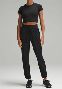 Black cropped athletic top paired with black drawstring pants. The pants feature cuffed ankles and a smooth, lightweight fabric.