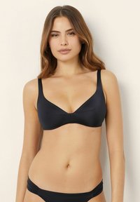 Černý bikiny top s nastavitelnými ramínky, hladkým materiálem a výstřihem ve tvaru V. Minimalistický design bez viditelné kovové součásti nebo vzorů.