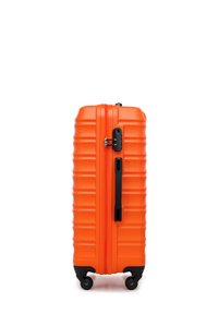 Valigia arancione rigida con texture rigata, chiusura a zip, maniglia laterale e quattro ruote nere per una facile manovrabilità.