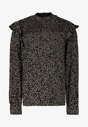 Black long-sleeve blouse featuring a speckled white pattern, ruffled shoulder details, and a smocked high neckline. Made from lightweight fabric.