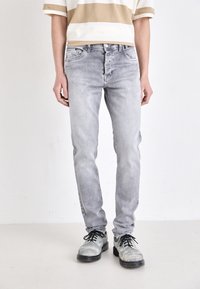 Grå denimjeans med smal passform, som har fem fickor och en urtvättad finish. Kombineras med svarta skor med texturerad detaljering.