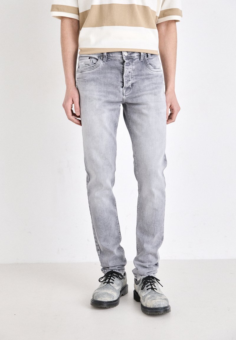 Grå denimjeans med smal passform, som har fem fickor och en urtvättad finish. Kombineras med svarta skor med texturerad detaljering.