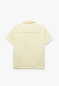 T-shirt med korte ærmer i lys gul krøllet stof, med spids krave og ryg-ydredetail. Glat tekstur, afslappet pasform.