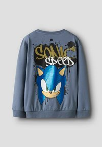 Sivi dukserica s velikom plavom grafikom lika sa nasmijanim licem, naglascima u obliku prskanja, te natpisima "SONIC" i "SPEED".