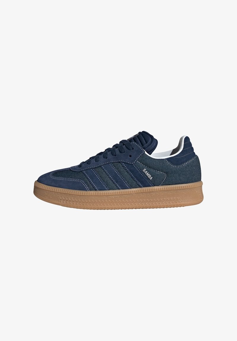 Mørkeblå sneakers med en overdel i ruskind og denim, med tre hvide striber, polstret krave og en struktureret sål i gummi.
