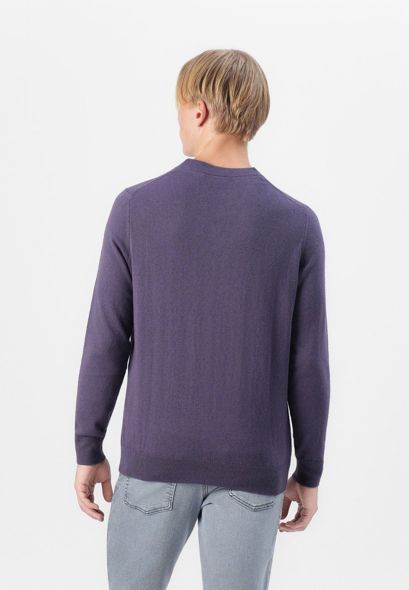 Fioletowy sweter z dzianiny z długimi rękawami, okrągłym dekoltem i prążkowanymi mankietami. Gładka tekstura, widok z tyłu, noszony z jasnoszarymi dżinsami.