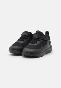 Baskets noires en mesh et matériau synthétique, dotées d'un bout arrondi, de lacets élastiques et d'une sangle en Velcro pour un maintien sécurisé.