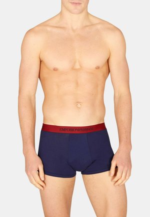 Boxer aderenti in cotone blu navy con fascia elastica rossa decorata con il logo "EMPORIO ARMANI". Design sagomato che enfatizza forma e comfort.