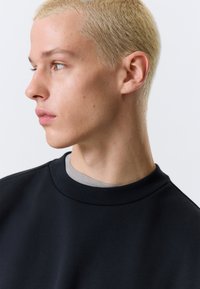 Dark navy sweatshirt with a round neckline, featuring a layered grey collar. Smooth fabric, minimalistic design, and no visible patterns or accents.