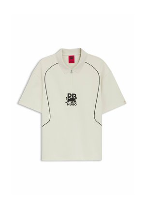 Polo manches courtes blanc cassé avec passepoil noir, col à zip demi-fermeture et logo noir "RB HUGO" avec un graphisme de taureau sur la poitrine.