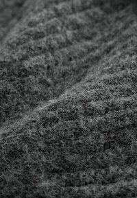 Grauer Stoff mit einer flauschigen, weichen Erscheinung, ausgestattet mit einer dichten Webart und feinen Fasern, die eine geschichtete, leicht unebene Oberfläche erzeugen.