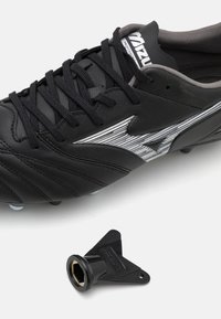 Scarpa da calcio in pelle nera con superficie texturizzata, lacci sottili e logo argentato. Include una chiave esagonale nera.