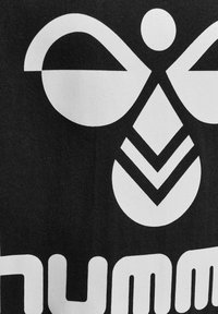 Czarna tkanina prezentuje odważny biały wzór graficzny z abstrakcyjnymi kształtami, w tym symetryczną postać oraz wzory w jodełkę.