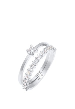 Due anelli d'argento intrecciati, uno con una pietra quadrata centrale e l'altro decorato con piccole gemme trasparenti lungo la banda.