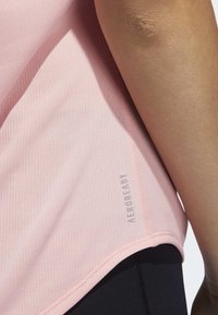 Rosa sporttopp med ett strukturerat, luftigt material, med sömdetaljer och "AEROREADY"-logotyp på sidan.