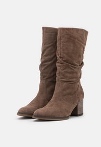 Hnědé měkké semišové kozačky ke kolenům s kulatou špičkou, texturovaným povrchem a blokovým podpatkem pro zvýšení výšky a stability.