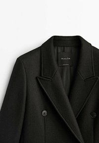 Manteau en laine noir croisé à double boutonnage avec de larges revers crantés et boutons noirs, étiquette Massimo Dutti, fabriqué au Portugal.