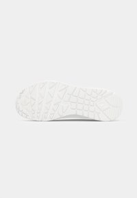 White sneaker sole with textured grip pattern, featuring triangular and square shapes for traction. Smooth edges with minimal design details.