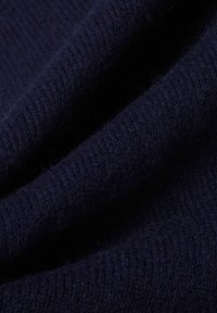 Dunkelmarineblaues Strickmaterial mit einer weichen, strukturierten Oberfläche und einem leichten Glanz, das feine Nähte und ein einheitliches Muster aufweist.