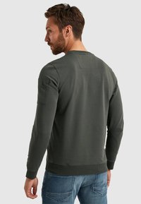 Sweatshirt verde scuro in misto cotone, con maniche lunghe, polsini a coste e taschino sulla manica sinistra. Design semplice.