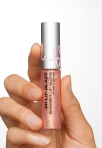Schimmernder Lipgloss in einer klaren, pinken, schimmernden Tube mit silbernem Metallverschluss; schwarze Schrift auf der Verpackung zeigt den Produktnamen deutlich an.
