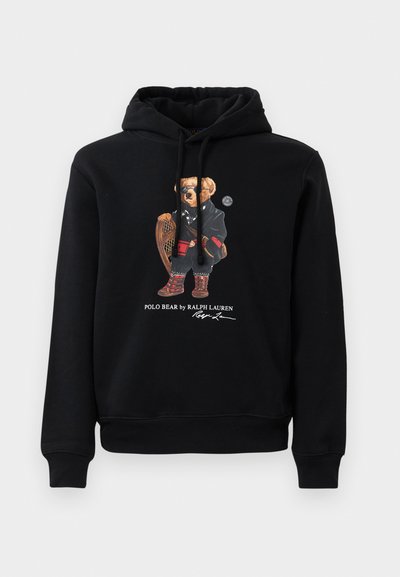 Černá mikina s kapucí, na které je medvěd v slunečních brýlích, s kabátem, botami a dřevěnou raketou, pod nímž je text "Polo Bear od Ralpha Laurena".