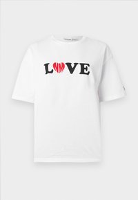 Λευκό βαμβακερό μπλουζάκι με την επιγραφή «LOVE» σε μαύρο, με μια κόκκινη καρδιά στη θέση του «O». Κοντά μανίκια και άνετη εφαρμογή.