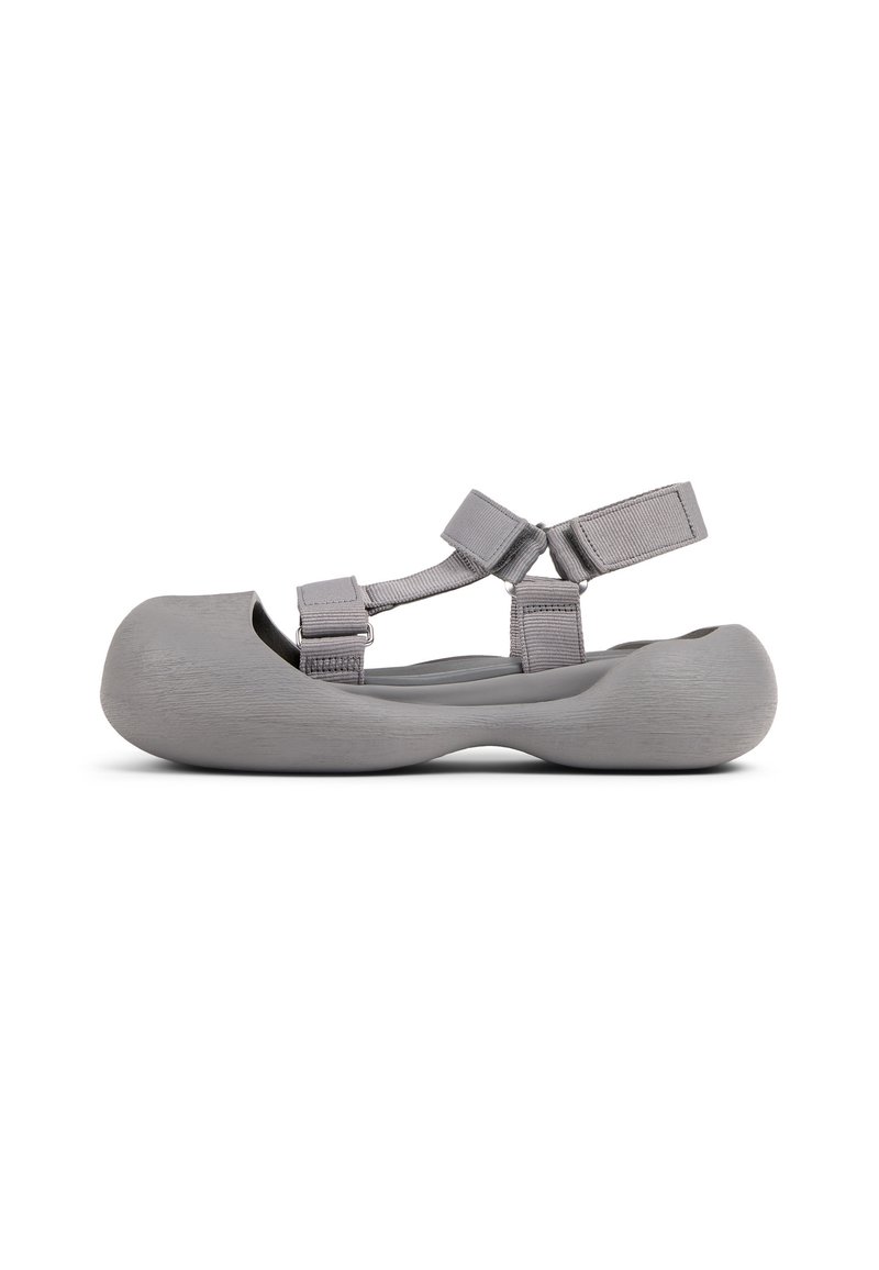Gray molded shoe with a rounded toe, textured surface, and adjustable strap. Contoured sole design enhances comfort and fit.