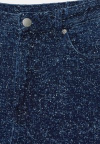 Tmavě modré džíny z denimu s texturovaným povrchem a skvrnitým vzorem, kovovým zapínáním na knoflík a klasickým pětikapsovým designem.