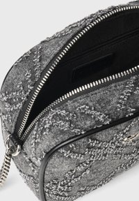 Borsa in tessuto grigio strutturato con cerniera argentata, forma arrotondata e dettagli neri. L'interno comprende una piccola tasca con cerniera e un'etichetta.