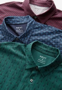Tres camisas de cuello en diferentes colores: burdeos con un patrón de puntos, azul marino con un patrón de abanicos y verde con formas geométricas.